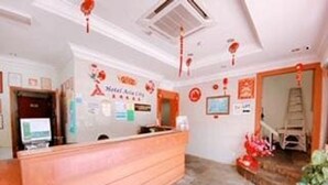 A hotel reception area with a wooden reception desk, a computer monitor, and a wall-mounted TV. - Hotel O Asia City (Kota Kinabalu)