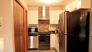 Una cocina compacta con electrodomésticos de acero inoxidable, microondas, horno y refrigerador.