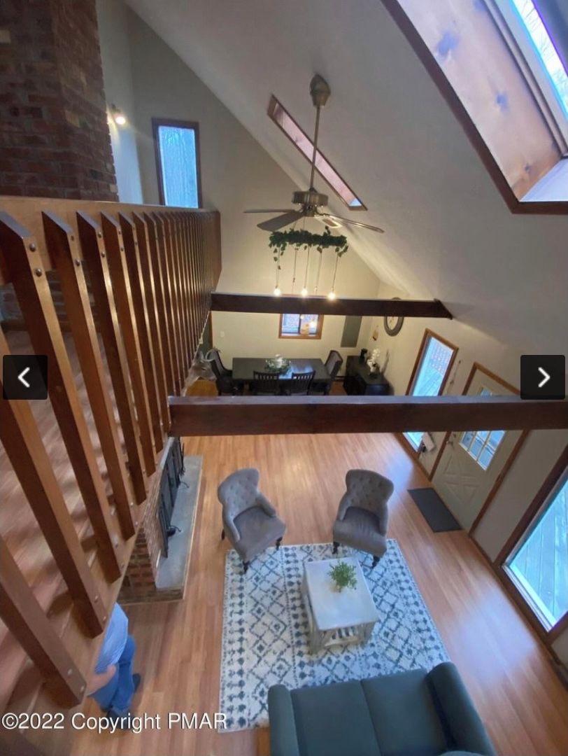 Ett rymligt vardagsrum i loftstil med högt i tak, en takfläkt och en matplats med bord och stolar.