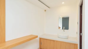 Ein modernes Badezimmer mit einem weißen Waschbecken, einem Holzwaschtisch und einem Spiegel mit blauer Vorhang.
