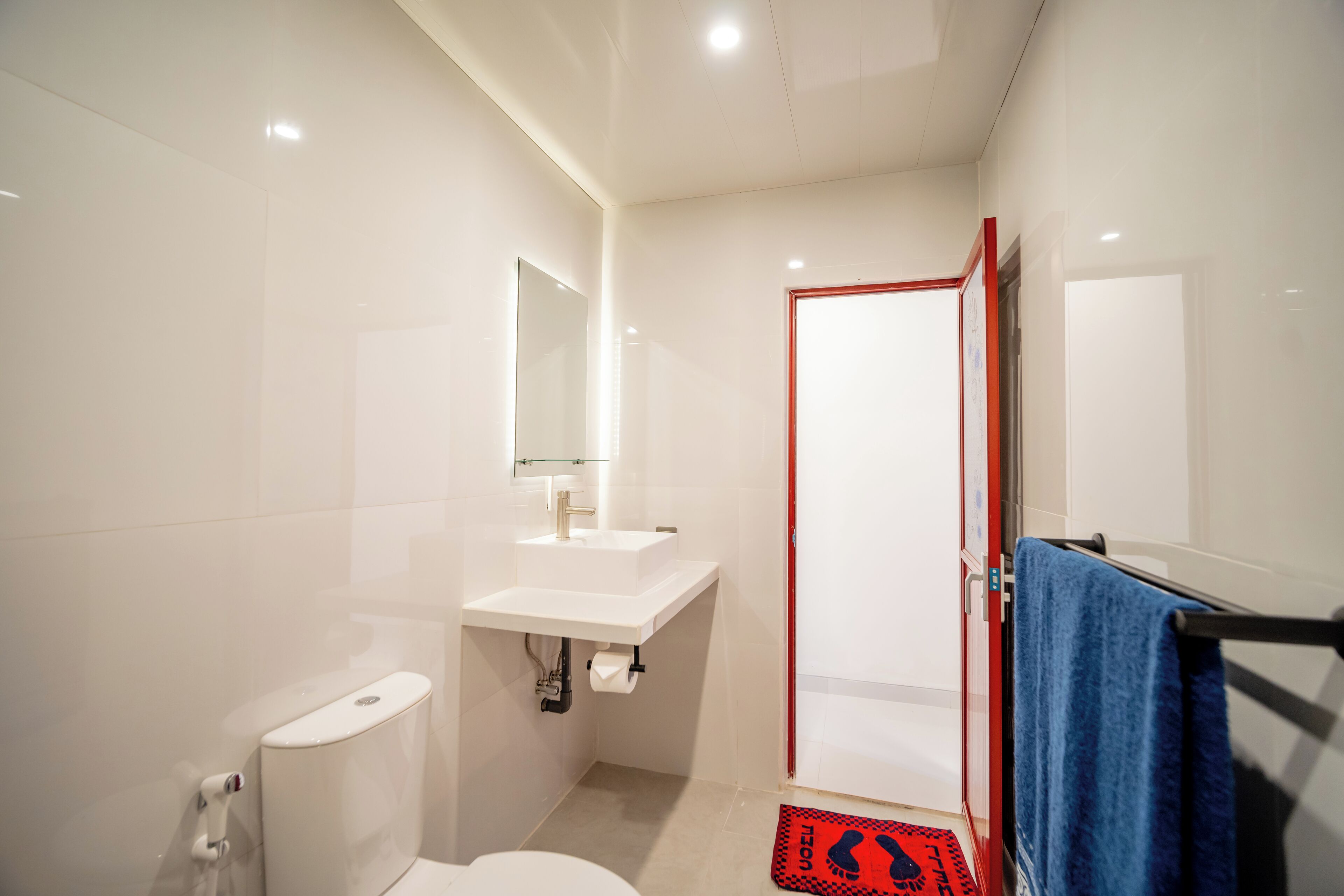 A modern bathroom with a toilet, sink, and mirror.