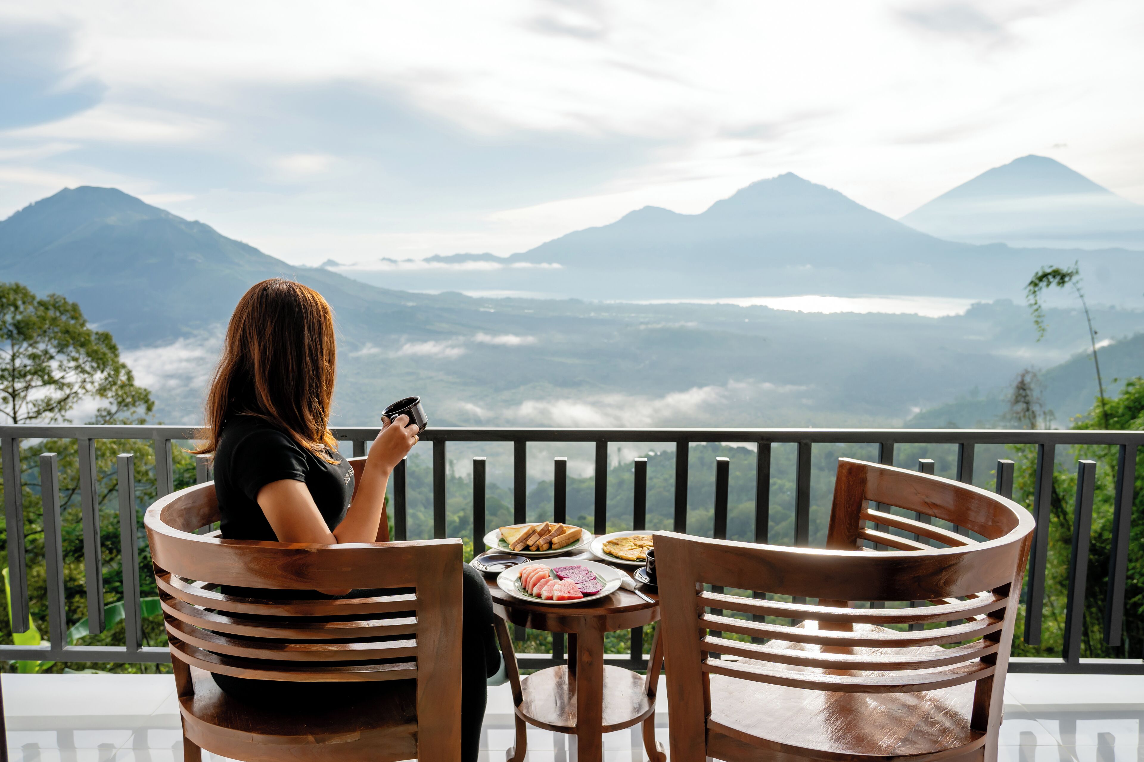 Una persona sentada a una mesa con vistas a montañas y un lago.