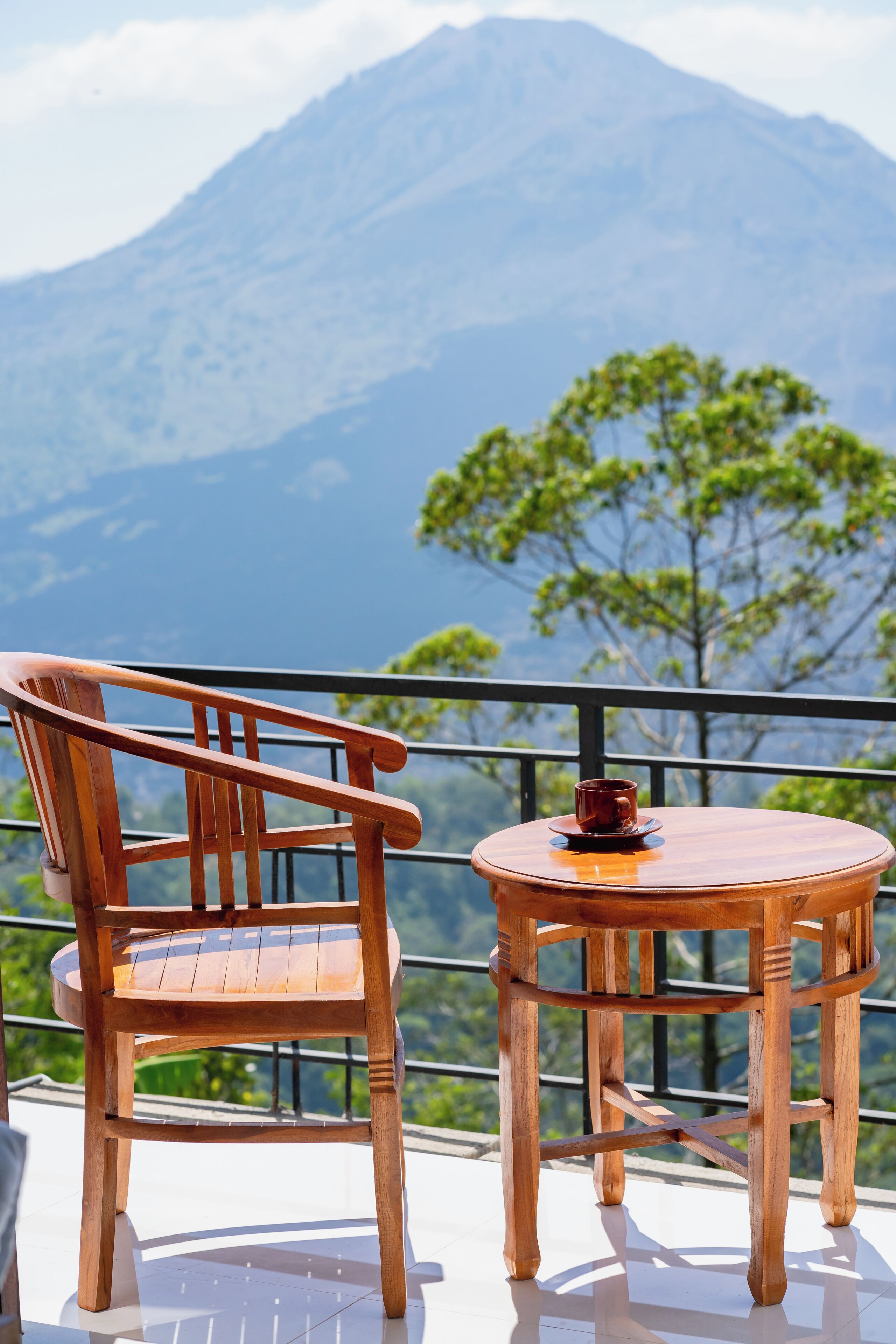 A wooden chair and table on a balcony with a mountain view.