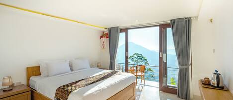 A bedroom with a large bed, a wooden nightstand, a chair, and a balcony with a view.