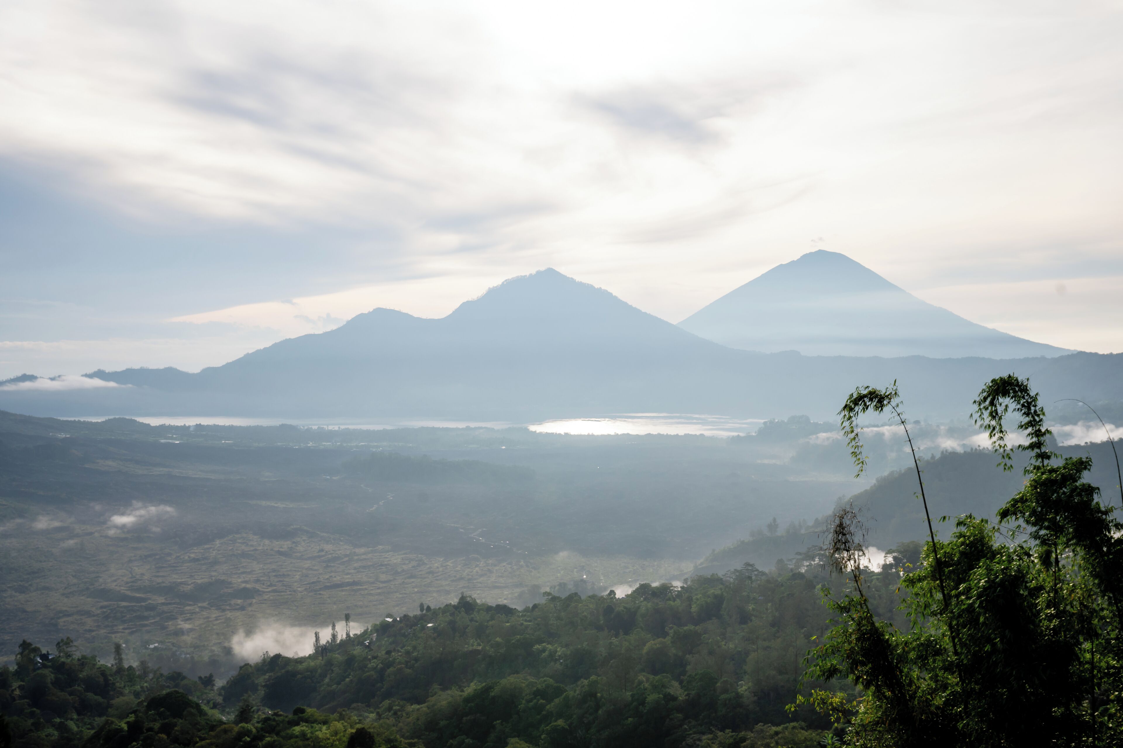 A mountainous landscape with two prominent peaks, a valley, and a body of water.