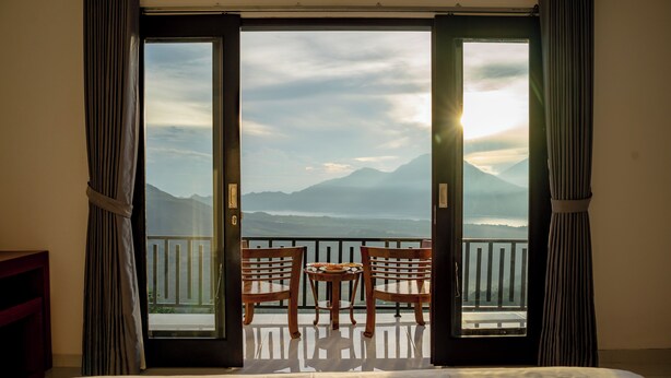Ein Zimmer mit Bett, Tisch mit Stühlen und einem Balkon mit Bergblick.