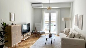 Ein modernes Wohnzimmer mit einer Couch, einem Fernseher und einer Pflanze.