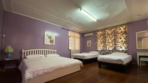 Quarto com duas camas individuais, piso de madeira, ar-condicionado fixado na parede e janela com cortinas.