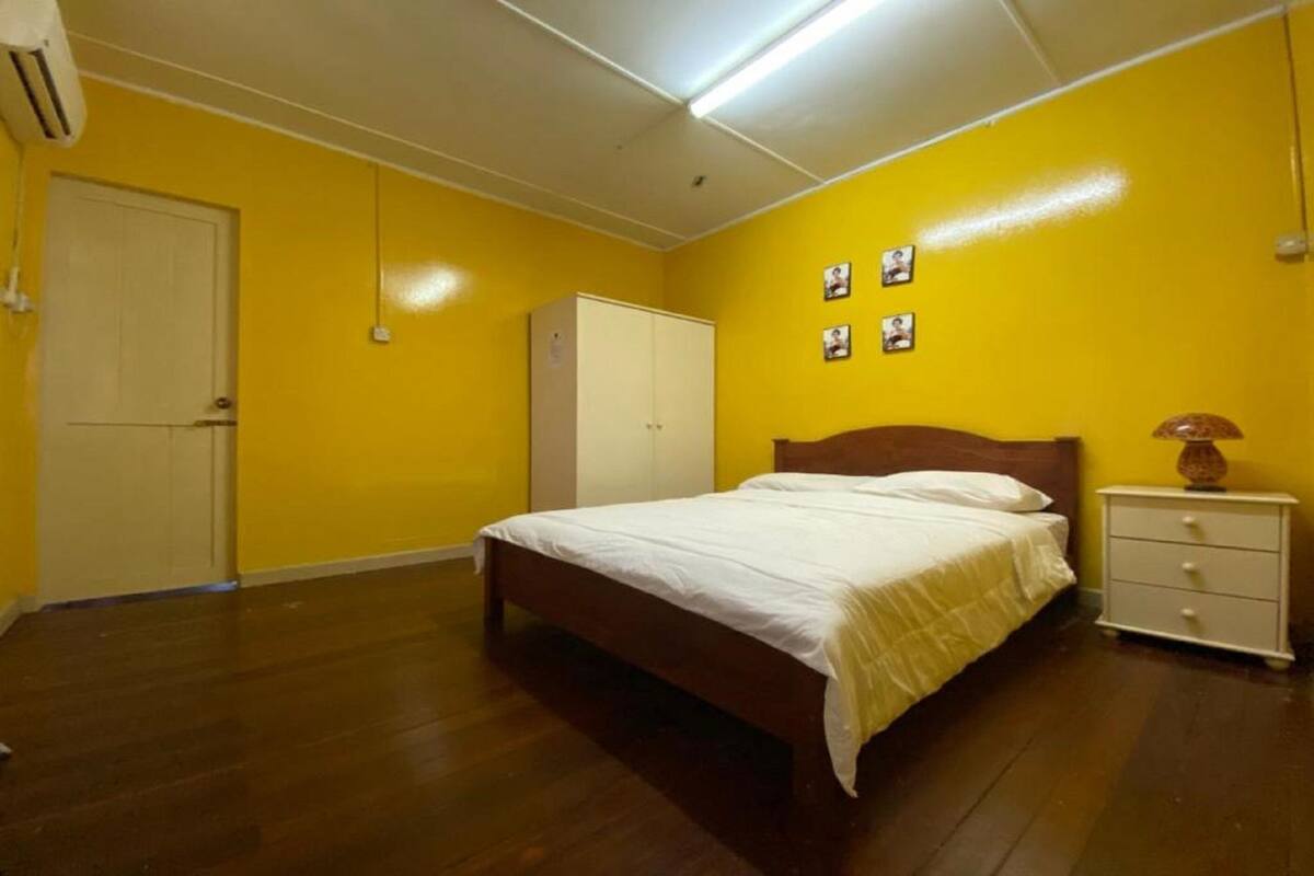A bedroom with a wooden bed, a white nightstand, a wardrobe, and a door.