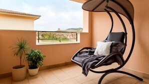 Ein Balkon mit einer Hängematte, Blumentöpfen und Blick auf die Landschaft.
