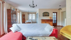Una habitación amplia con una cama grande, un sofá rojo, un sillón amarillo y un comedor con mesa y sillas.