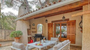 Un patio exterior con mesa lista para comer, una parrilla y una zona de estar con bancos.