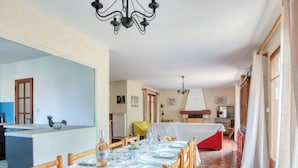 Un comedor con una mesa dispuesta para cuatro, una cocina al fondo y un pasillo que conduce a una sala de estar.
