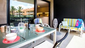 A modern dining area with a glass table, chairs, and a sofa with colorful cushions. - Golden Ray by Interhome (Jávea)