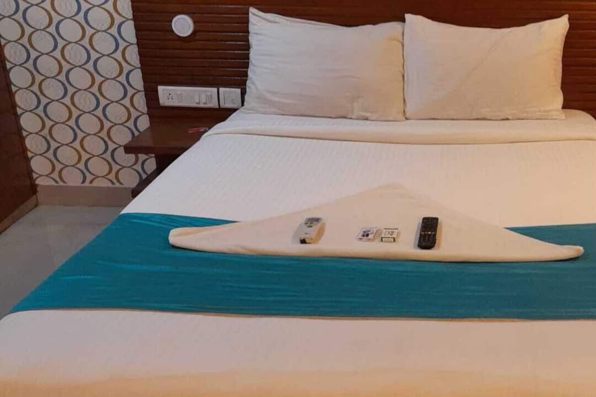 A hotel room with a bed, a nightstand, and a wall with a circular pattern.