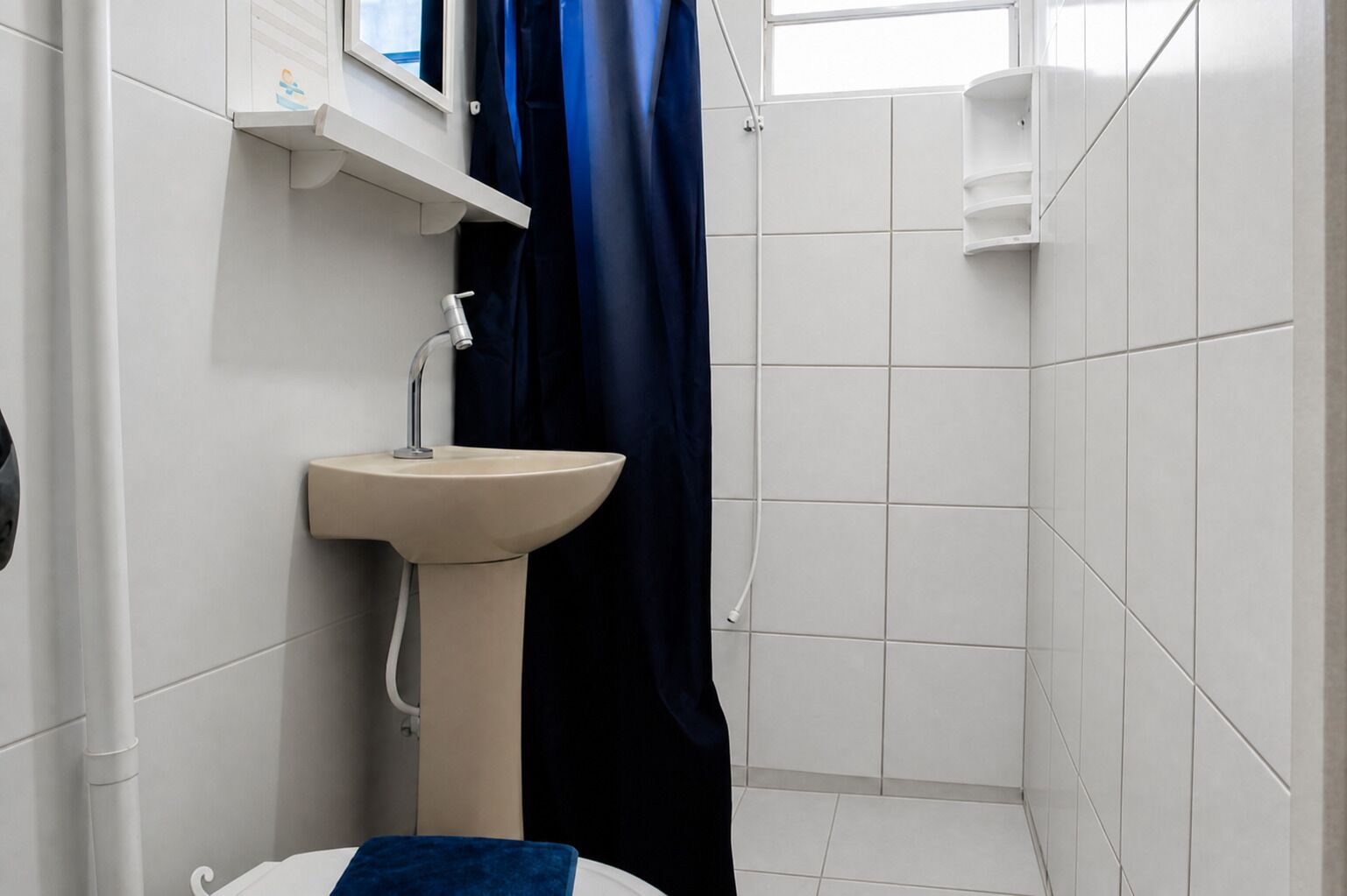 A bathroom with a sink, a mirror, a shower curtain, and a window.