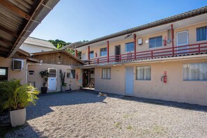 A building with a gravel courtyard, a dog lying on the ground, and a bicycle parked outside. - Residencial Ponta Norte (Florianópolis)