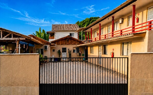 Un patio amurallado con edificios, un extintor y una barandilla roja.
