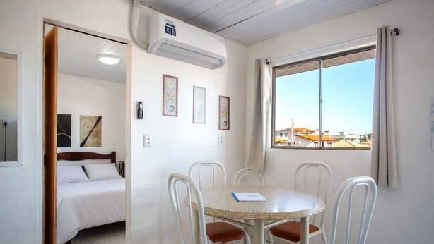 Une chambre avec un lit, une table à manger et des chaises, une fenêtre donnant sur un beau paysage et un appareil de climatisation.