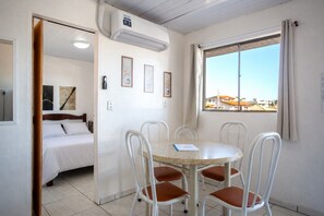 Una habitación con cama, mesa de comedor y sillas, ventana con vistas y aire acondicionado.