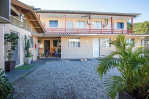 A two-story building with a covered entrance, a gravel driveway, and a parked bicycle. - Residencial Ponta Norte (Florianópolis)