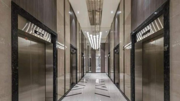 A modern hallway with glass doors, a polished floor, and a central light fixture.