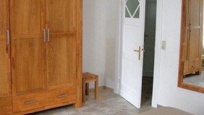 A room with a wooden wardrobe, a small wooden stool, and a white door leading to another room. - Ferienwohnung Leuchtfeuer (Eckernförde)