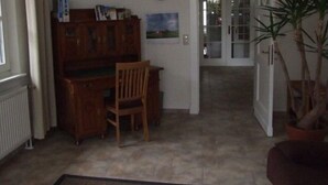 A hallway with a wooden desk and chair, a radiator, a door leading to another room, and a potted plant. - Ferienwohnung Leuchtfeuer (Eckernförde)