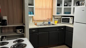 A compact kitchen with a white stove, black cabinets, a microwave, and a sink. - Small Space with a BIG View!!! (Redfield)