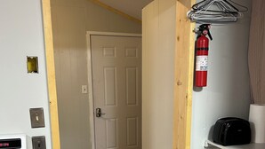 A small, narrow room with a wooden door, a white stove, a fire extinguisher, and a shelf with a fan. - Small Space with a BIG View!!! (Redfield)