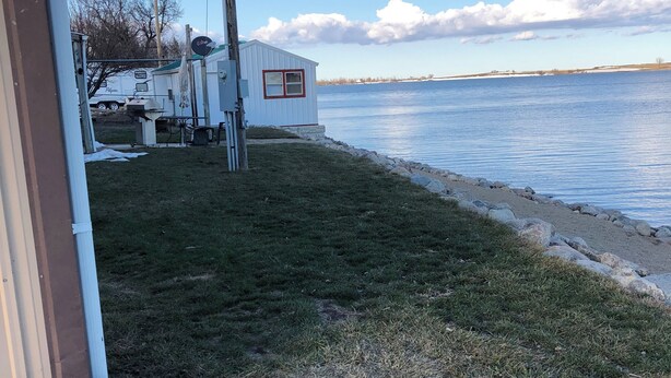 A lakeside property with a grassy lawn, a small shed, and a dock extending into the water. - Small Space with a BIG View!!! (Redfield)