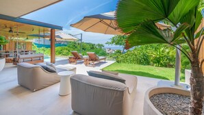 Amplia zona de estar al aire libre con asientos cómodos, piscina y vista al océano.
