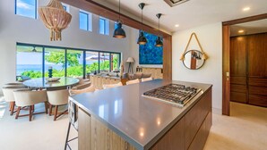 Cocina moderna con una isla grande, comedor con sillas y vistas al océano.