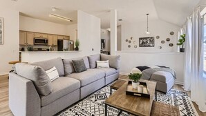 A modern living room with a grey sofa, a wooden coffee table, and a patterned rug.