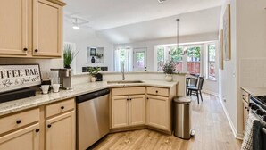A modern kitchen with a central island, built-in cabinets, and a coffee bar sign.