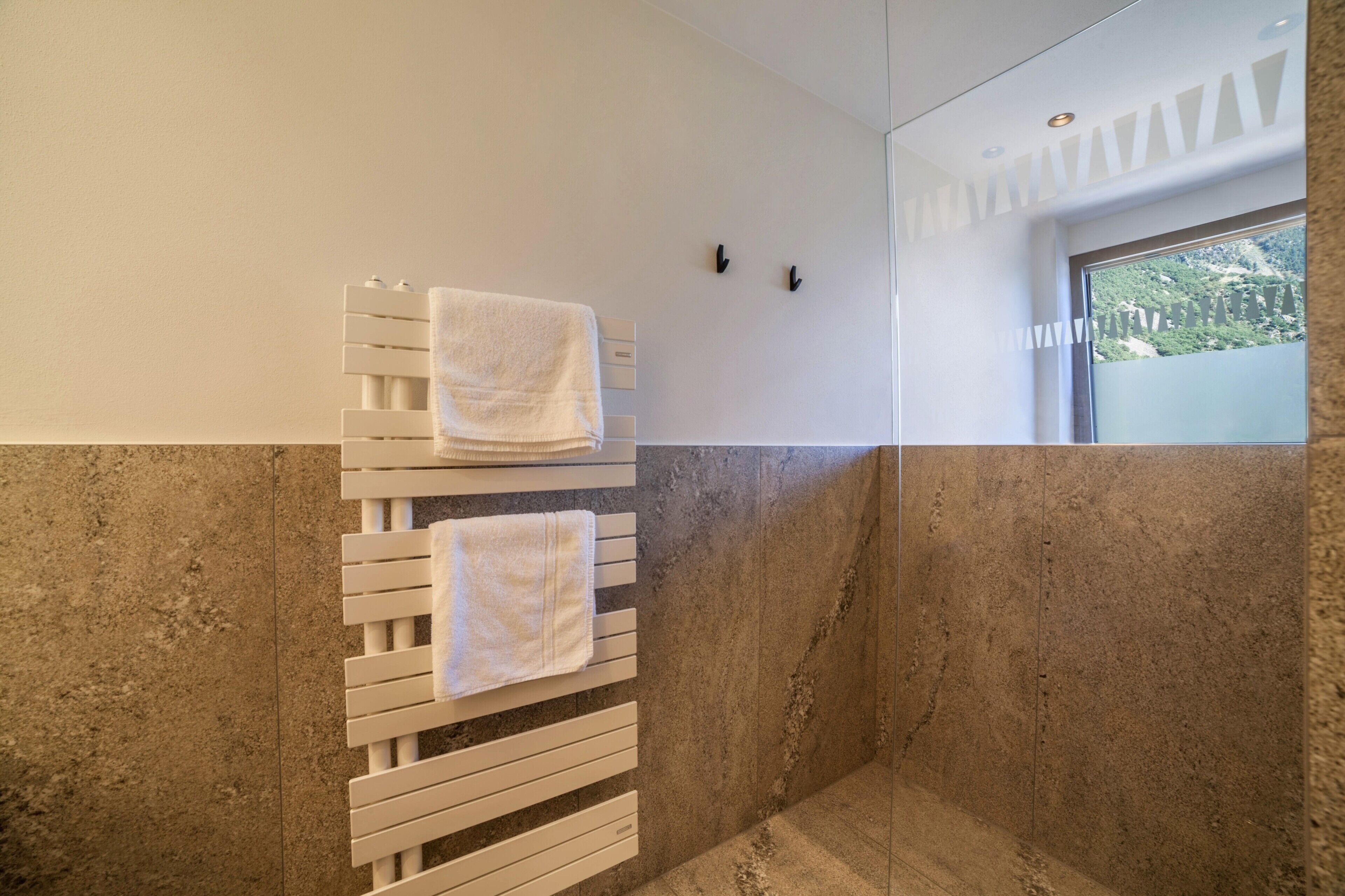 Une salle de bain équipée d’un porte-serviettes, d’un espace douche et offrant une vue sur la verdure environnante.