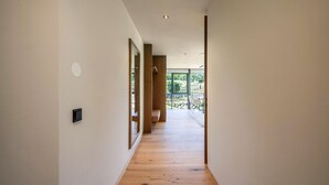 A modern interior with a wooden floor, a long hallway, and a view of greenery outside. - Apartment "Natur Romantik Annalena" with Mountain View, Private Terrace & Wi-Fi (Castelbello-Ciardes)
