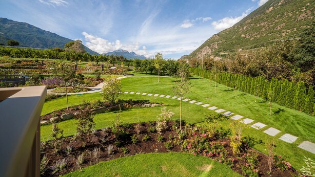 A landscaped garden with a winding path, a small pond, and a view of mountains. - Apartment "Natur Romantik Annalena" with Mountain View, Private Terrace & Wi-Fi (Castelbello-Ciardes)