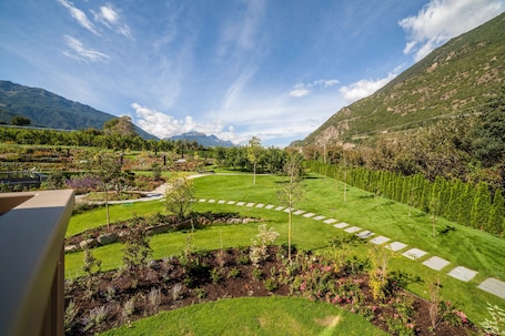 A landscaped garden with a winding path, a small pond, and a view of mountains.. Apartment "Natur Romantik Annalena" with Mountain View, Private Terrace & Wi-Fi