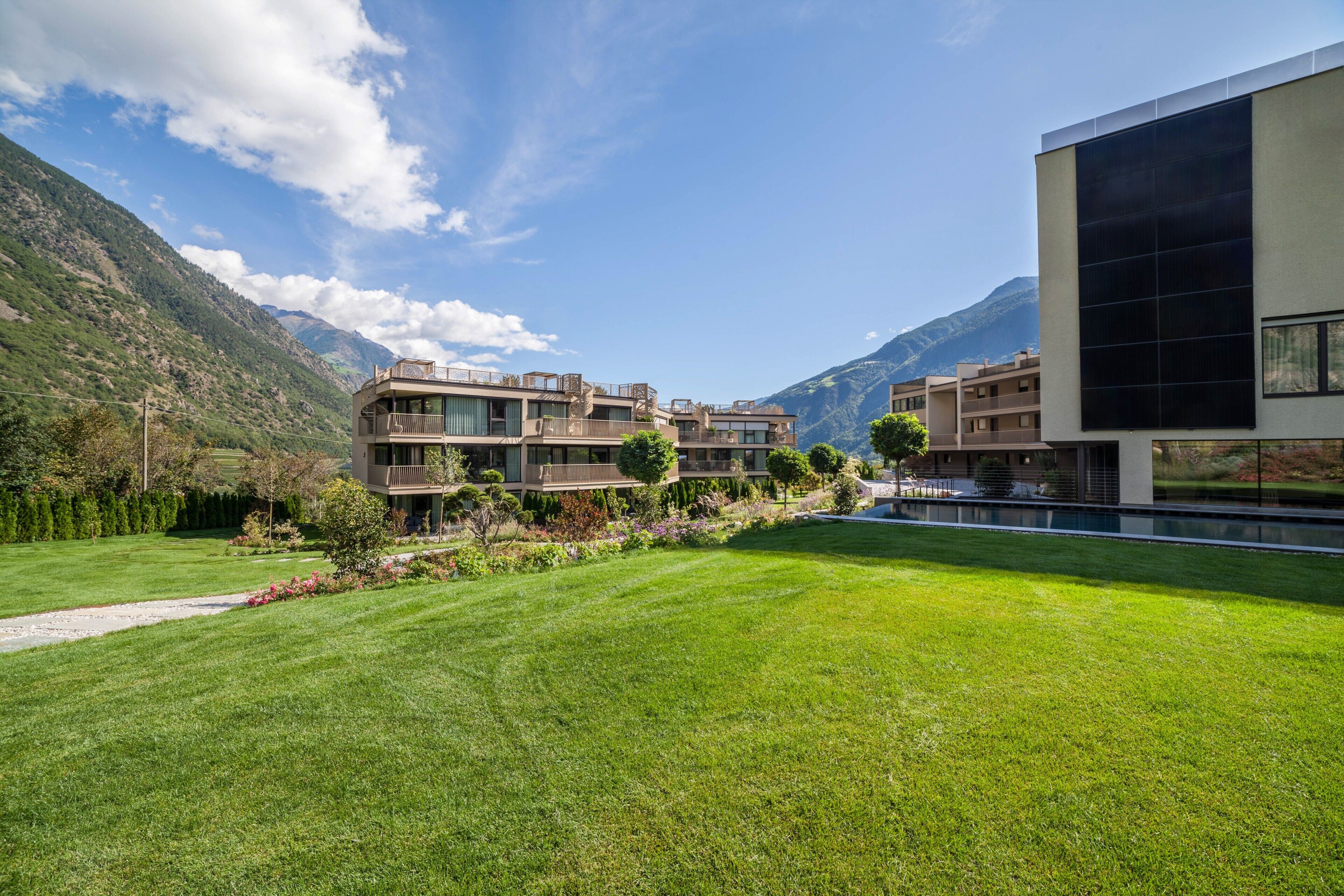 A modern building with multiple balconies, a well-maintained lawn, and mountains in the background. - Apartment "Natur Romantik Annalena" with Mountain View, Private Terrace & Wi-Fi (Castelbello-Ciardes)