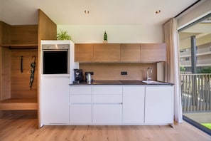 Uma cozinha compacta com forno embutido, cafeteira e pia.