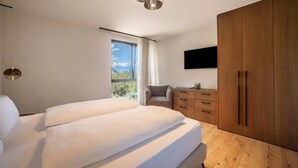 A modern bedroom with a large bed, a wooden wardrobe, a desk, and a TV mounted on the wall. - Apartment "Natur Romantik Annalena" with Mountain View, Private Terrace & Wi-Fi (Castelbello-Ciardes)
