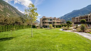 A modern building with multiple balconies, surrounded by a well-maintained lawn and a mountain backdrop. - Apartment "Natur Romantik Annalena" with Mountain View, Private Terrace & Wi-Fi (Castelbello-Ciardes)