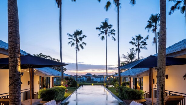 A resort with a pool, lounge chairs, and palm trees.
