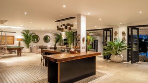 A spacious living area with a central wooden bar, a pool table, and a comfortable seating area.