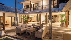 A two-story house with a balcony, outdoor seating area, and a pool.