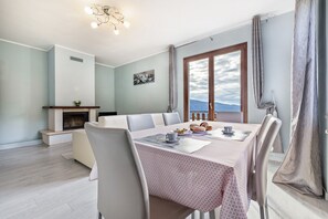 Un comedor con una mesa dispuesta para cuatro, chimenea y vistas a la montaña.