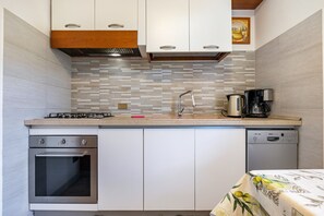 Una cocina compacta con horno empotrado, lavavajillas, cafetera y salpicadero de azulejos.