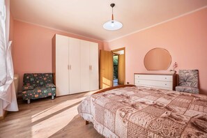 A bedroom with a bed, a wardrobe, a dresser, a mirror, and a sofa.