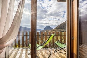 Un balcón con vistas a un paisaje montañoso y una masa de agua.